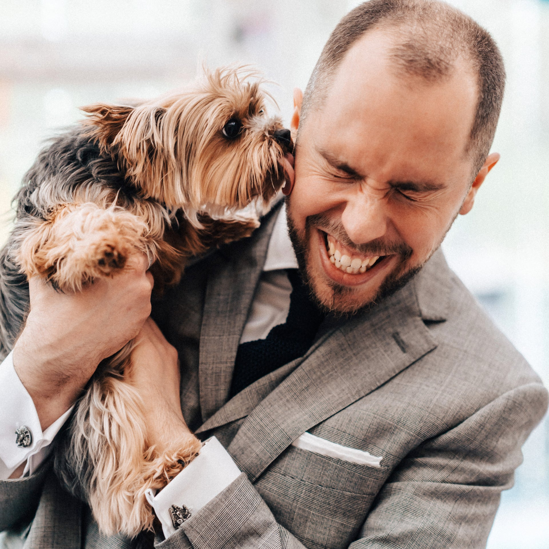 A photograph of Tim Montague holding his parents' dog, a Yorkshire Terrier named Fizzy, licking Tim's cheek